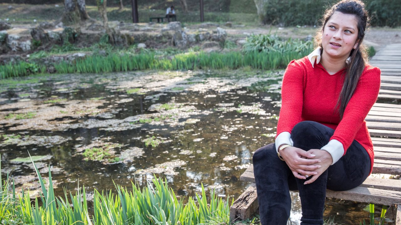 Uma, 18 ans, nous confie son histoire, assise au bord de l'eau dans jardins botaniques de Katmandou.