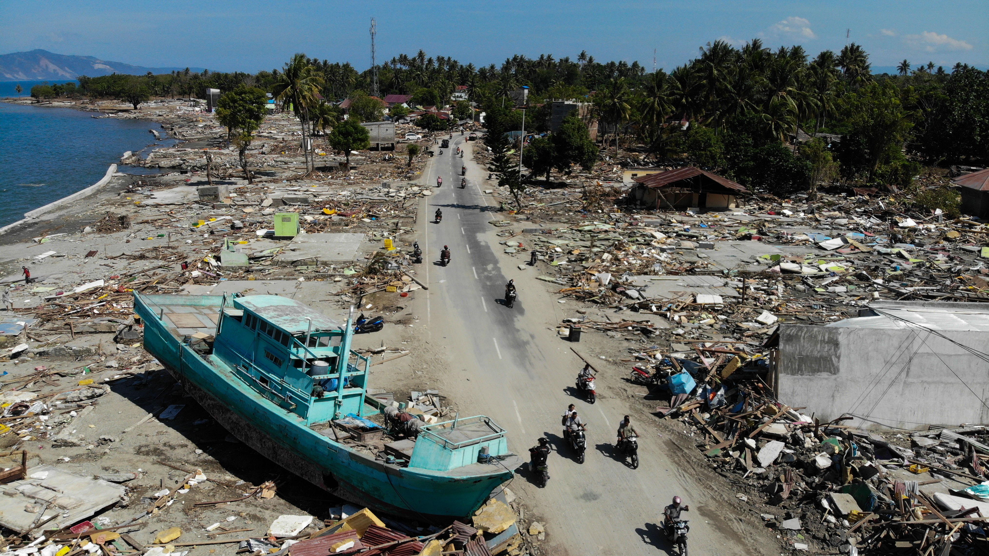 Le 1er octobre 2018, des personnes passent devant un bateau échoué et des bâtiments effondrés à Palu, après le tremblement de terre et le tsunami qui ont frappé la région le 28 septembre.