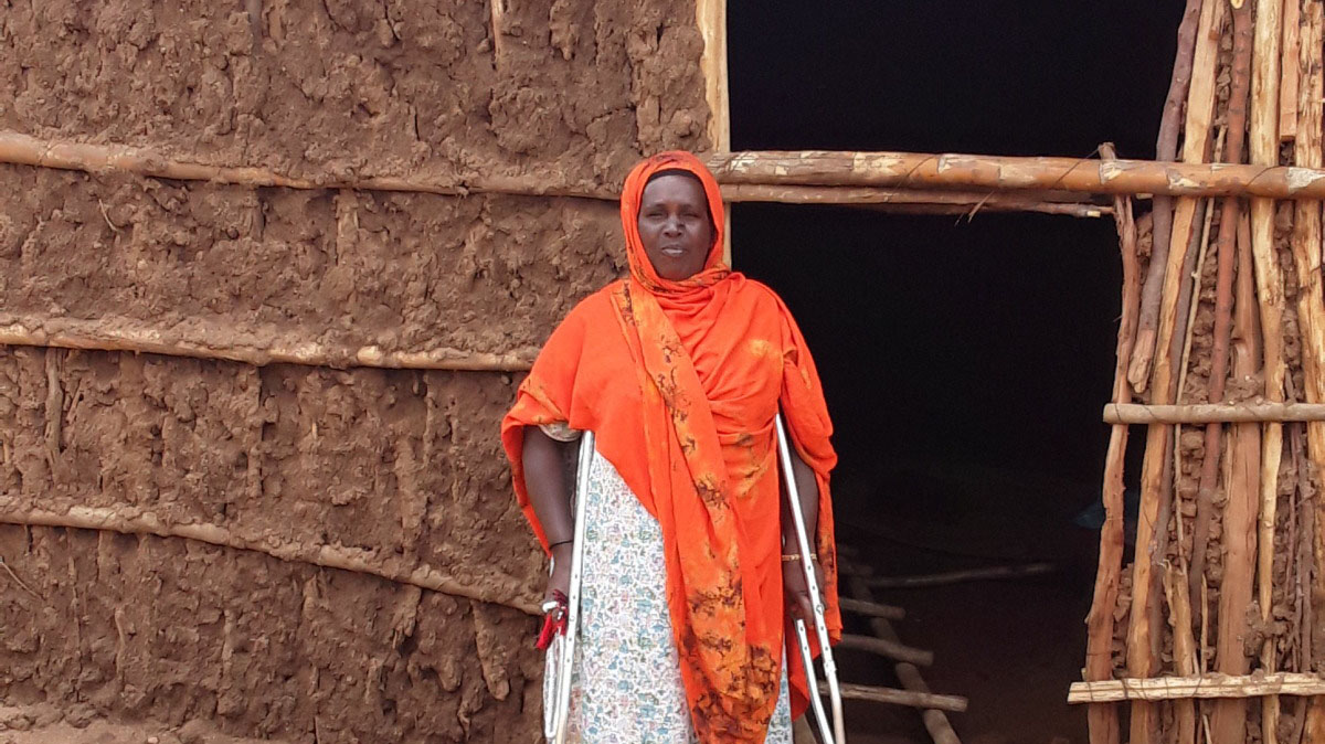 Meryam in front of her house