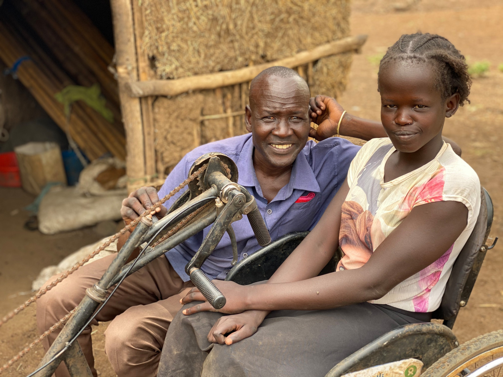 Nyadouth (à droite) utilisant le tricycle mobilisateur fourni par HI, avec son oncle (à gauche). 