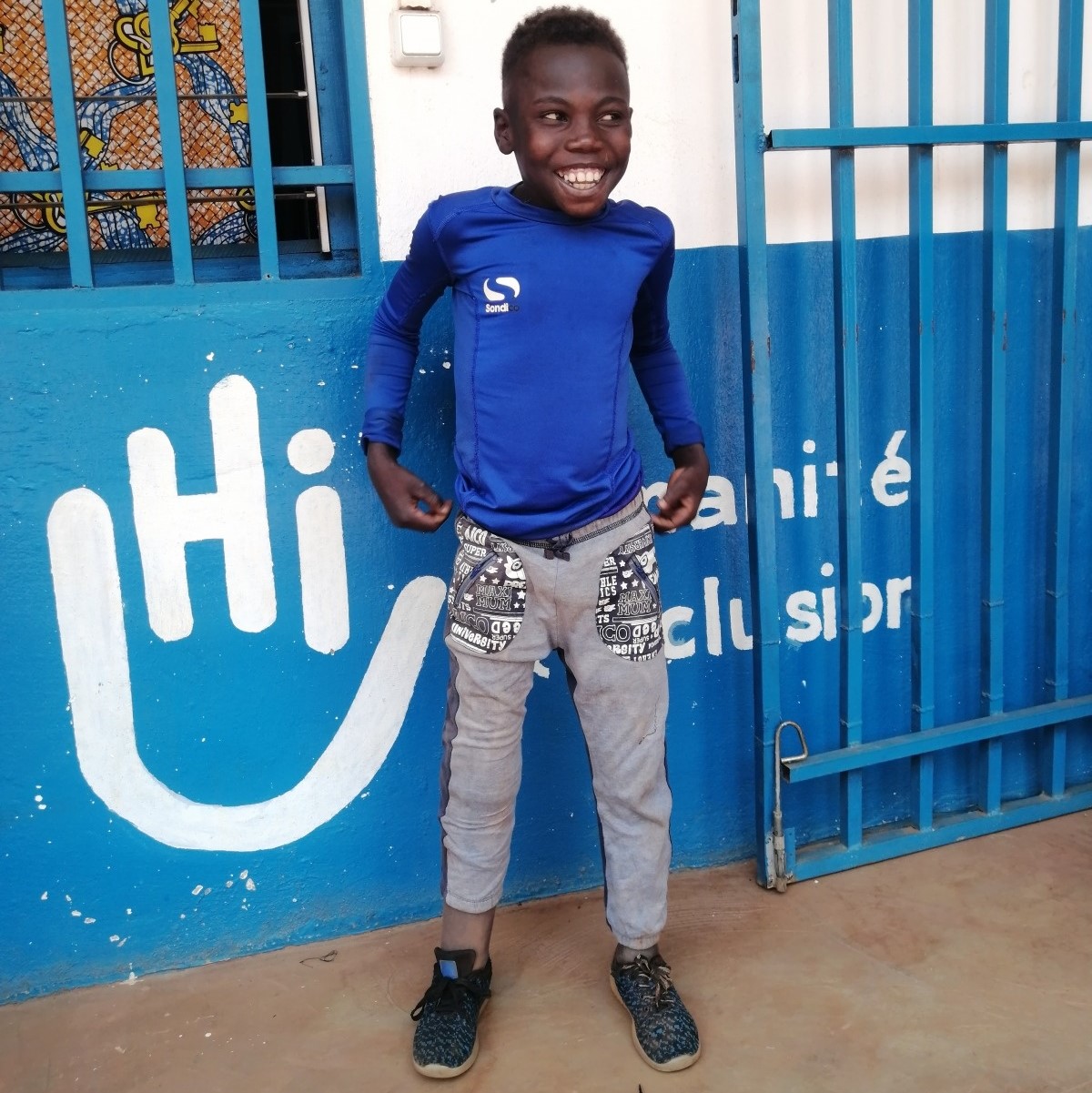 Un petit garçon se tient debout devant l’hôpital régional de Bambari et montre sa prothèse.