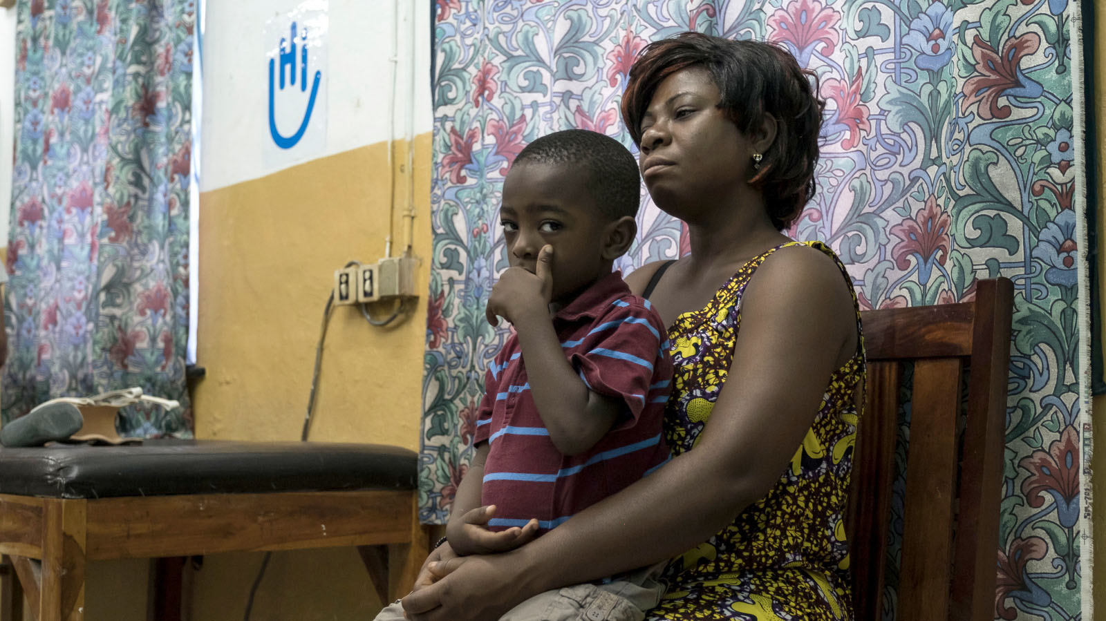 Gbede Xola Olympio prends son fils Koffi Olympio, 4 ans, pendant qu'ils attendent le docteur pour scanner ses jambes au CNAO le 5 Juin 2018 à Lomé, Togo.