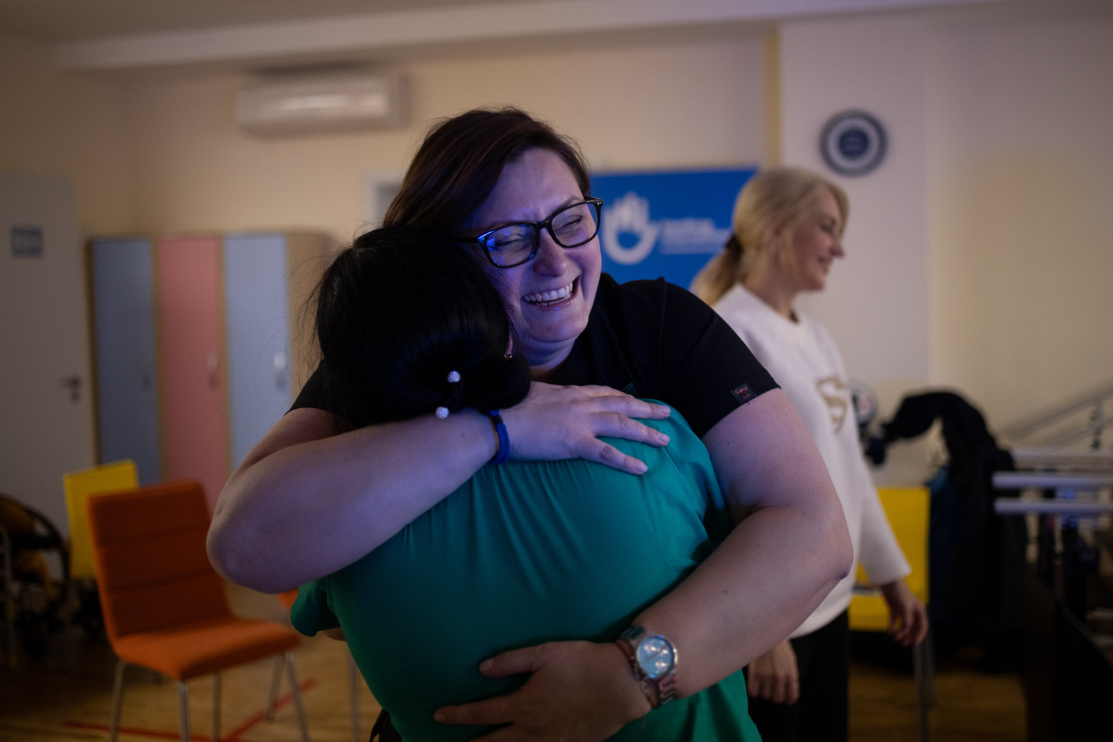 Deux femmes se serrent dans les bras et elles sourient.