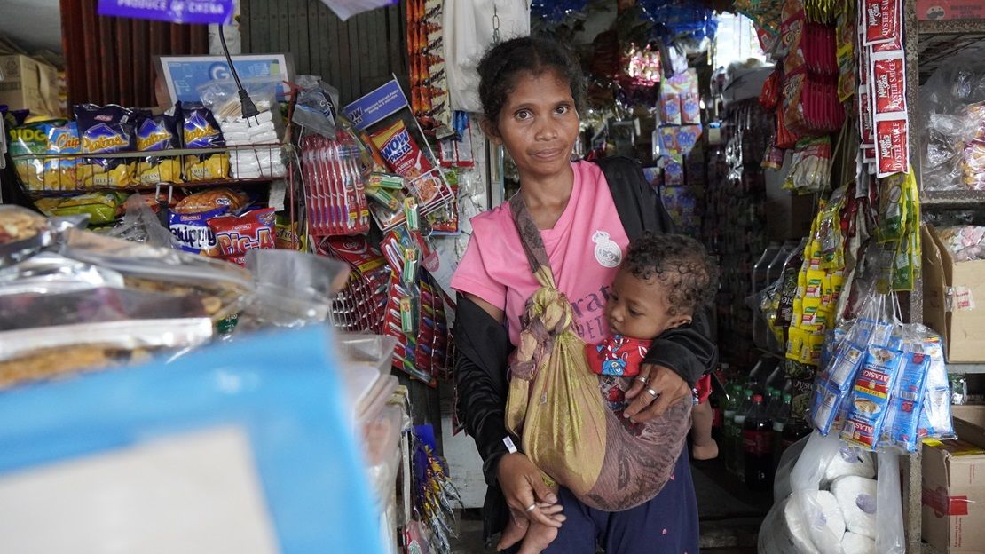 A young woman carries her baby in a shop in the Philippines.