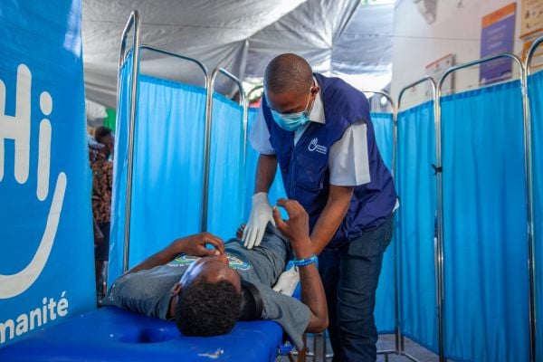 HI volunteers help a woman to collect her items at an NFI distribution point in Mozambique