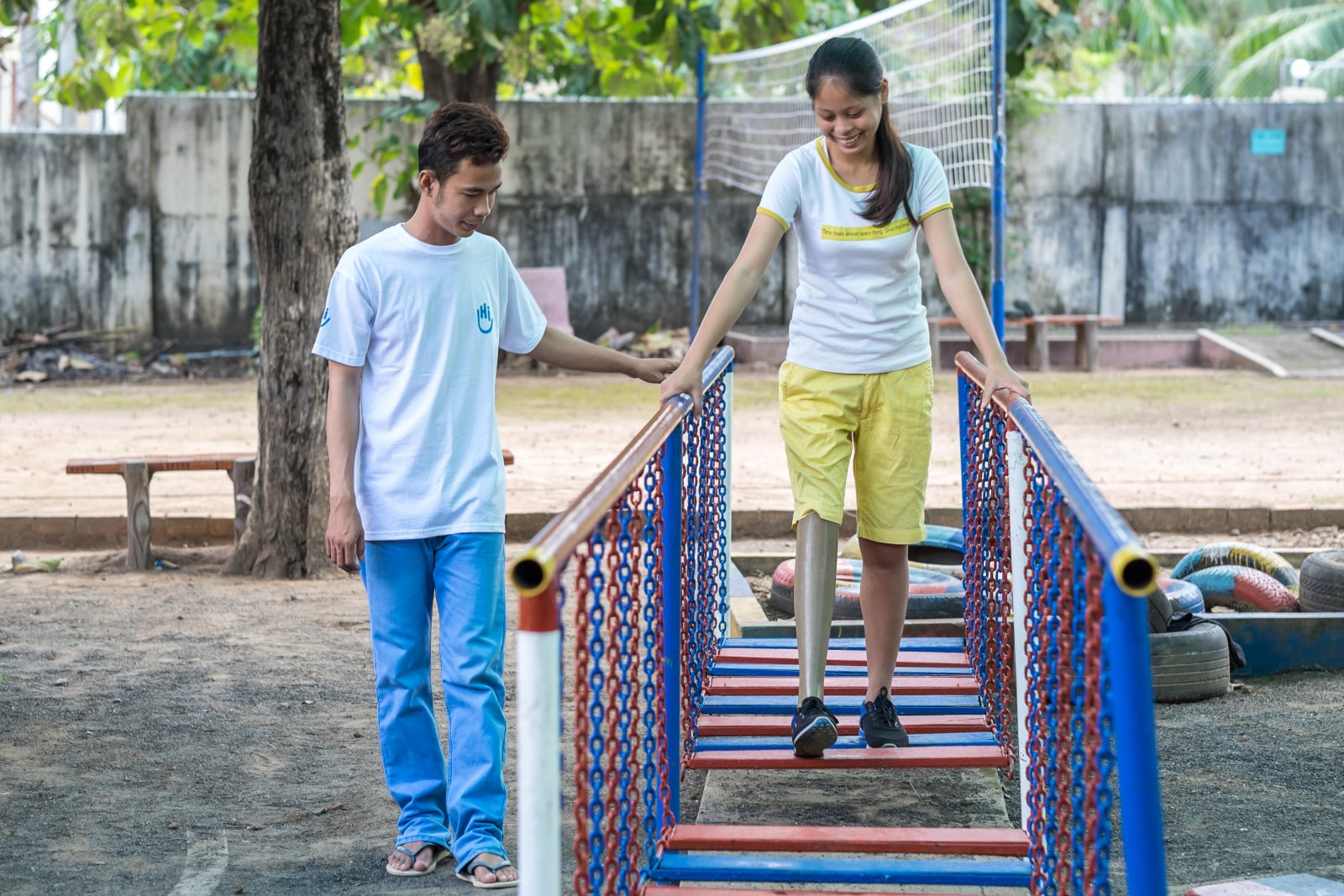A woman with a disability being helped to walk outside