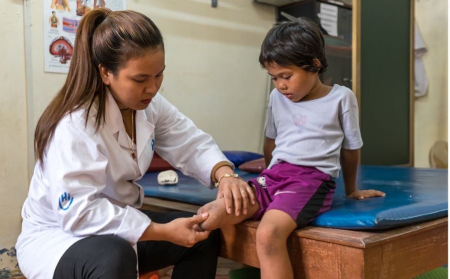 Female doctor helping a little boy put on a prosthetic