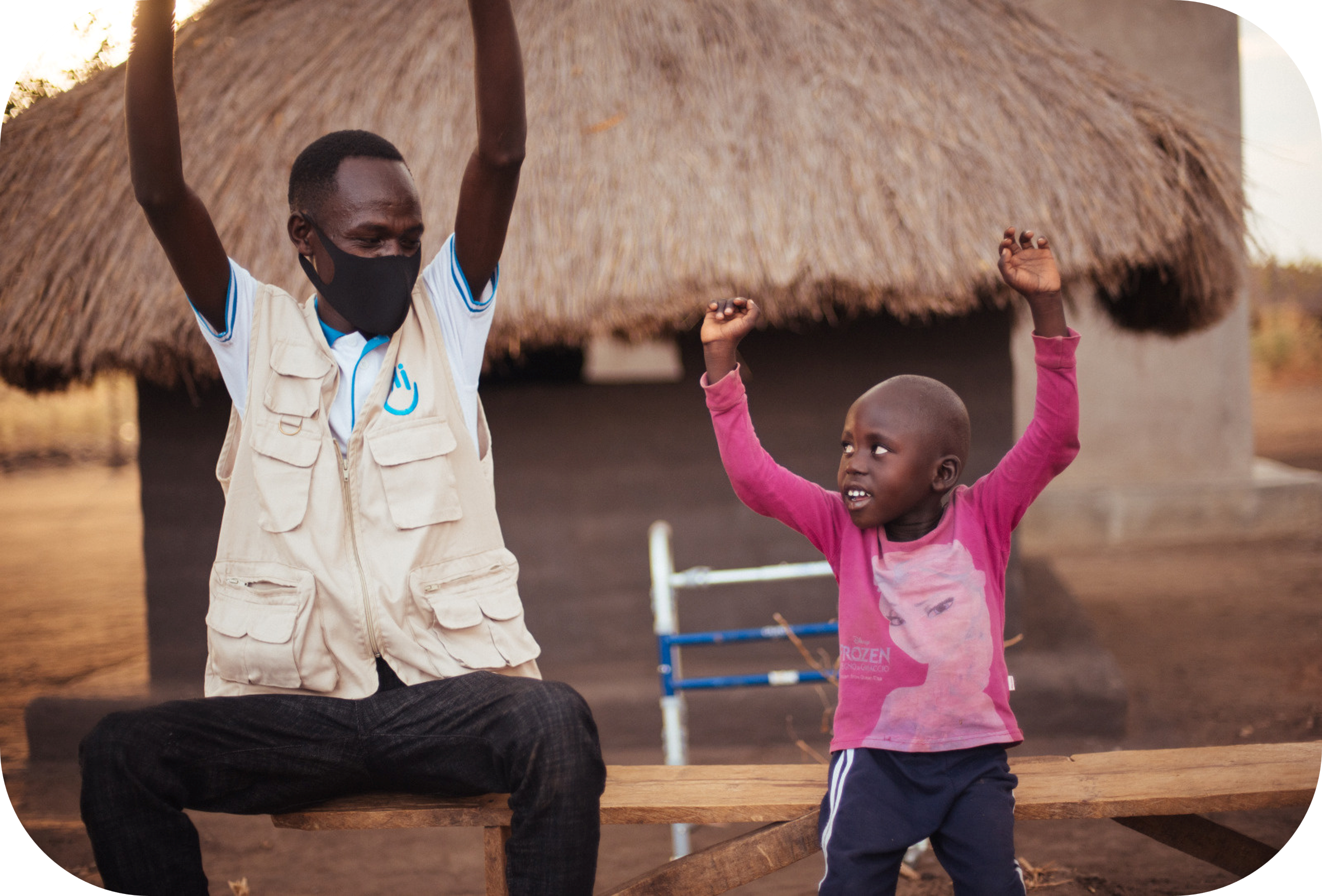 A child and an adult happily raise their arms in the air