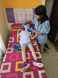 During a therapy session, Laura Giovana massages Tamara's face with a facial massager. © Y. Franco / HI