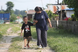 Ambika, marchant avec Prabin, 6 ans, qui vient de recevoir une nouvelle prothèse. © A.Thapa / HI