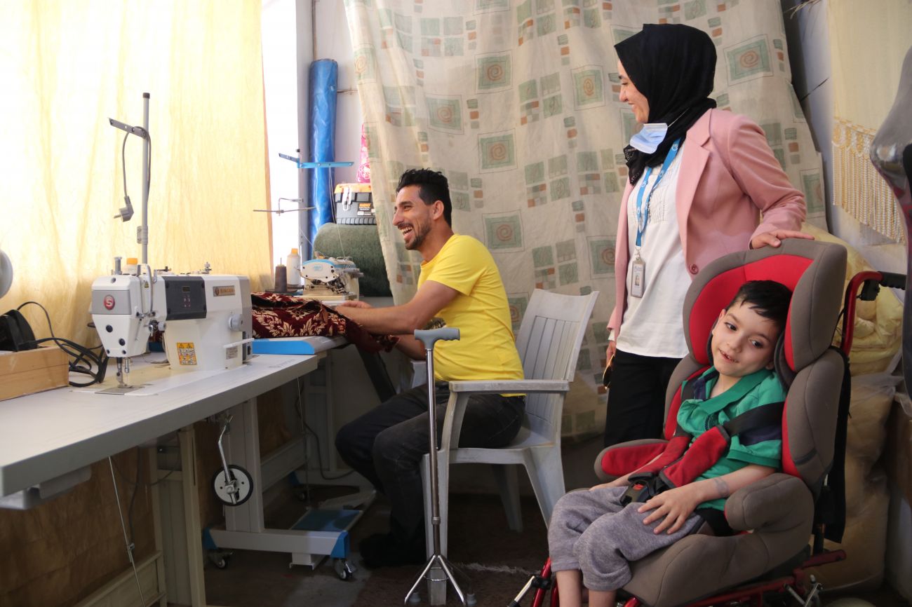 Le personnel de HI rend visite à Ahmad et à l'un de ses enfants dans son atelier de couture à domicile. © D.Ginsberg / HI