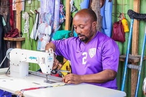 Christian Ngongo, un réfugié congolais, coud un vêtement dans son atelier de couture. © Imani Rugenge / HI