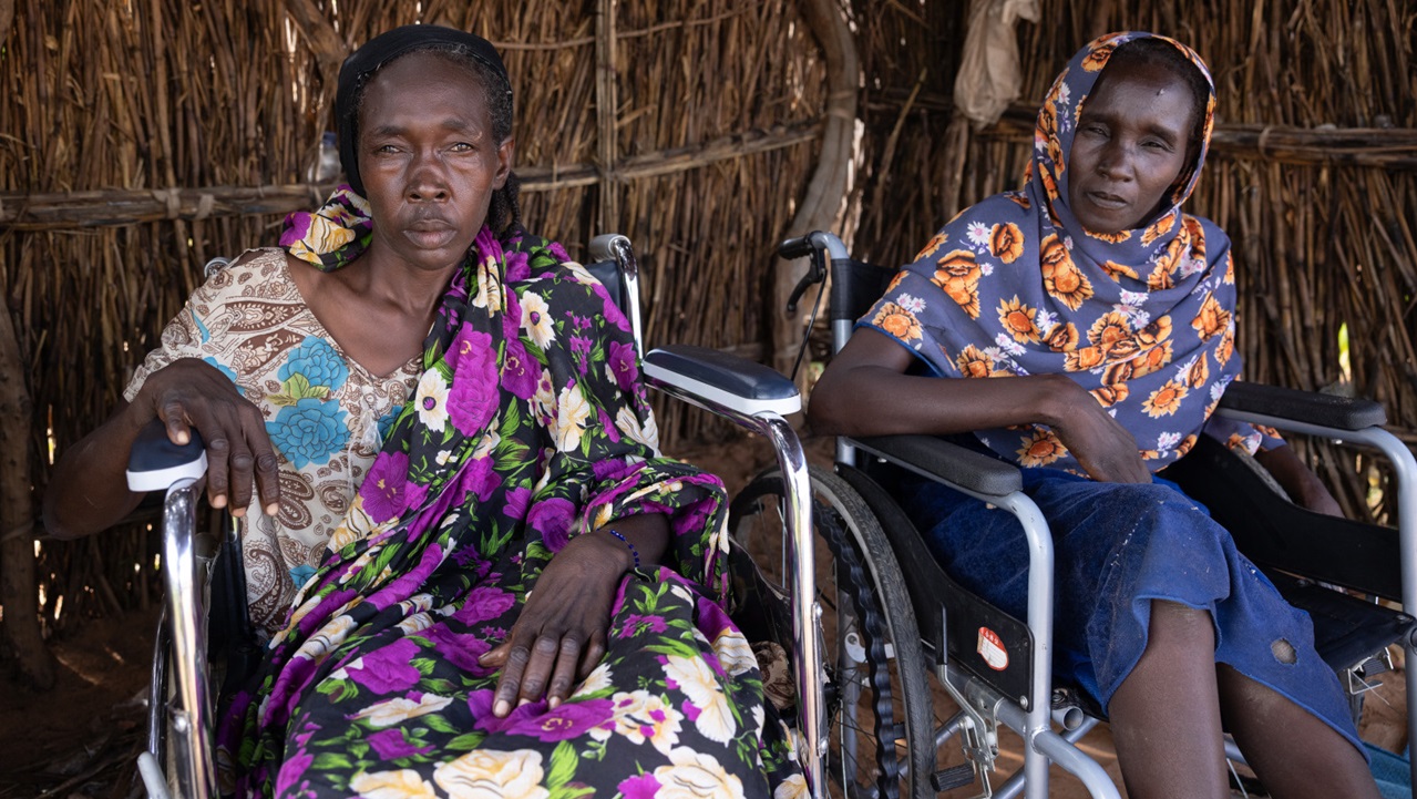 Two disabled women in wheelchairs stare at the camera.