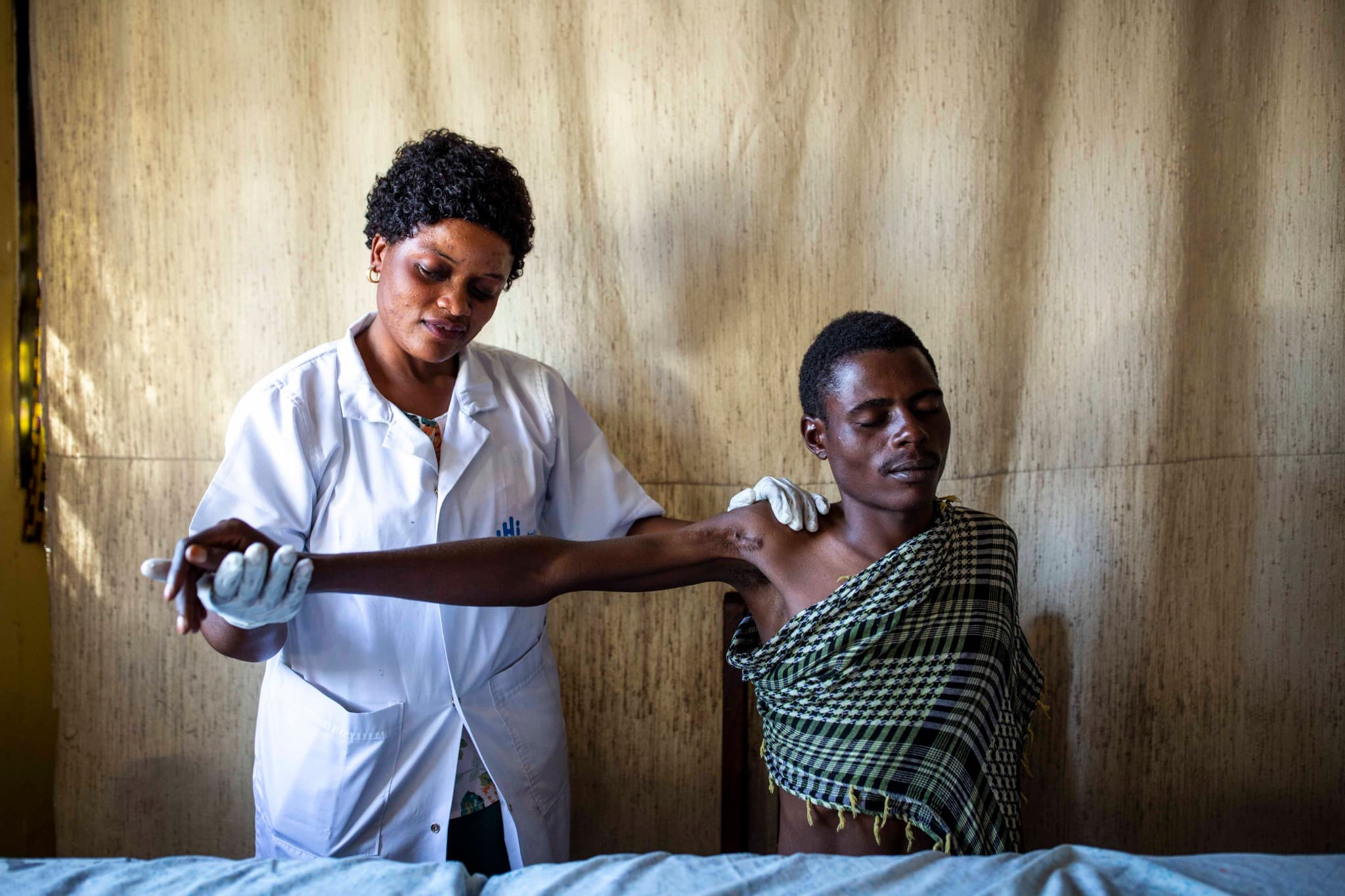 Héritier, 23 ans, victime d'une attaque dans sa maison, suit des séances de réadaptation avec Noela, physio avec Humanité & Inclusion, en République démocratique du Congo (Goma).