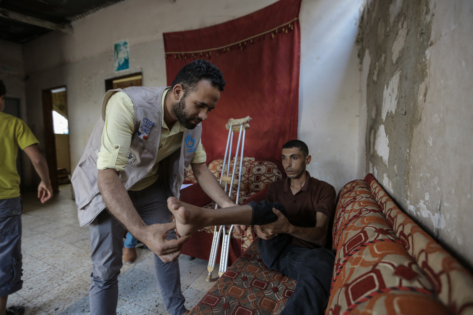 Un physiothérapeute de HI ausculte la jambe d’Alaa 
