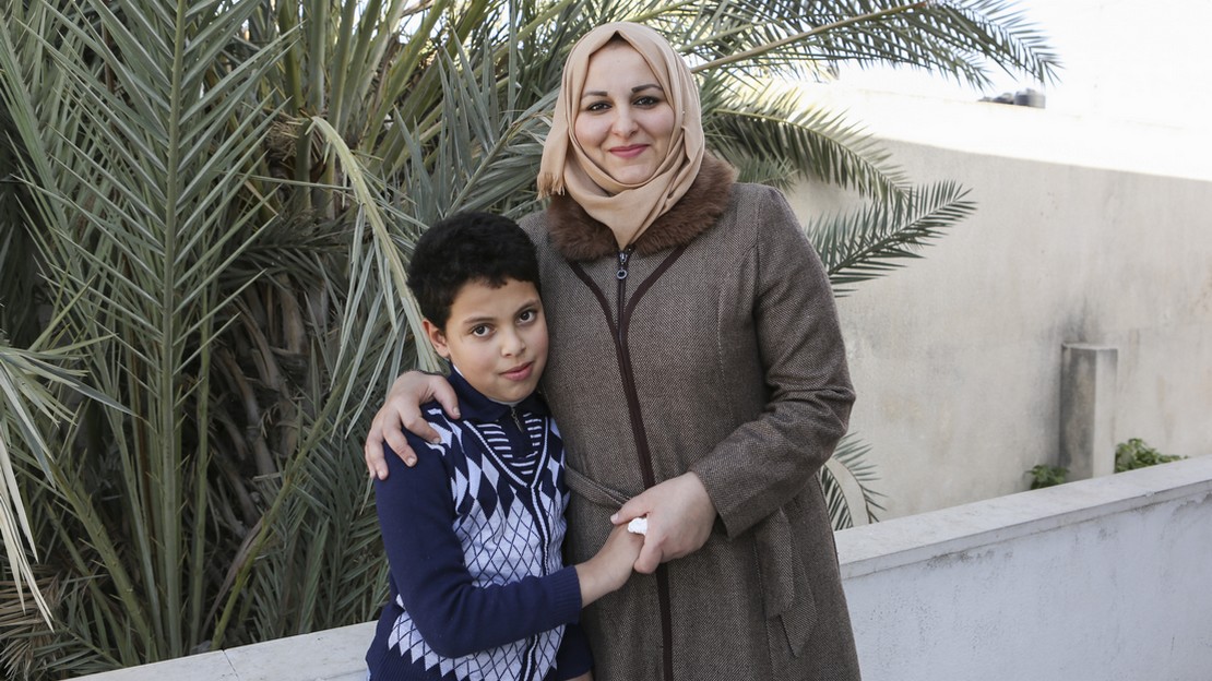Suha, et son fils Mahmoud, devant l’école soutenue par HI 