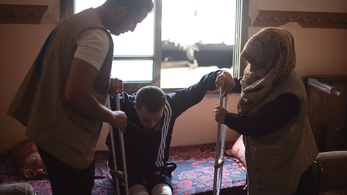 Les employés de HI fournissent des aides à la mobilité et des séances de rééducation à un homme blessé à Gaza, 2018