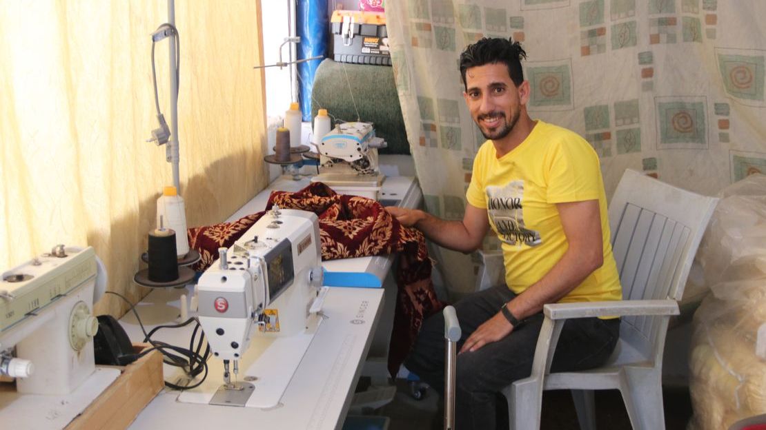 Ahmad, 29 ans, est assis dans son atelier de couture à la maison. © D.Ginsberg / HI