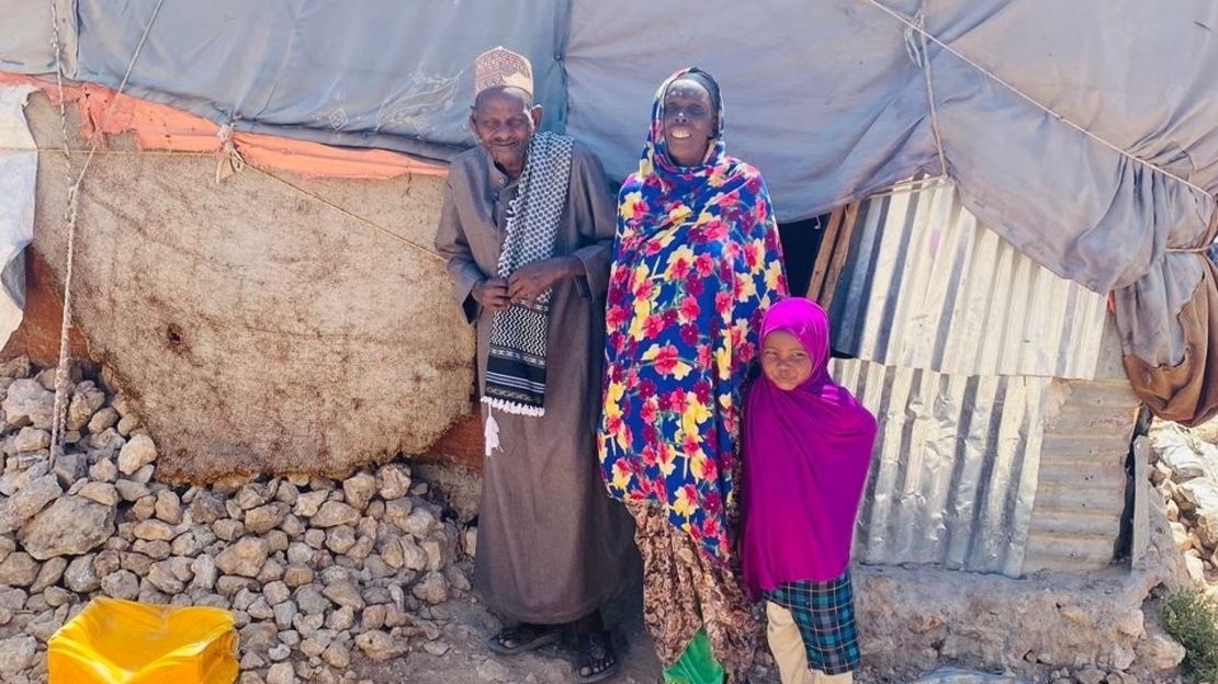Amina (au centre) pose avec son mari (à gauche) et l’un de leurs trois enfants (à droite) devant leur nouvelle maison, dans un camp de déplacés à Hargeisa. 2022.